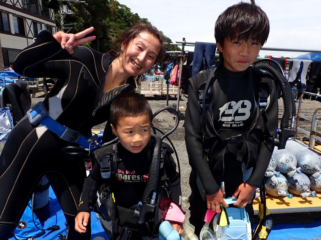 ダイビングキャリア25年・ダイビングインストラクター歴20年の現役幼稚園教諭の女性インストラクターのユウ先生と、ウエットスーツを着て体験ダイビングに挑戦する子どもたち